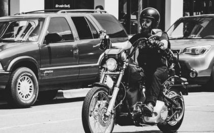 Man with beard and helmet on a motorcycle.