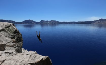 Man taking a risk diving off of a cliff.