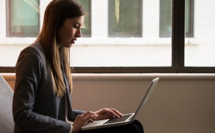 Woman sits with laptop.