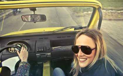 Woman in car smiling about saving money.