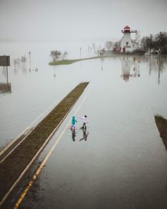 Children walking in flood waters near lighthouse.