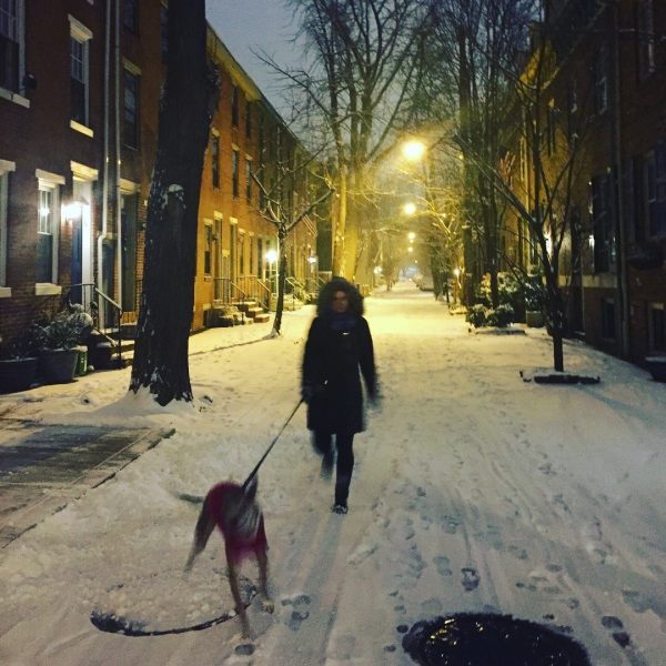 Woman walking dog in snow.