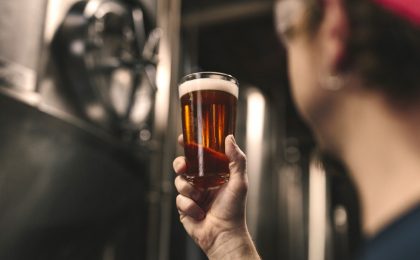 Man holding beer in a brewery.