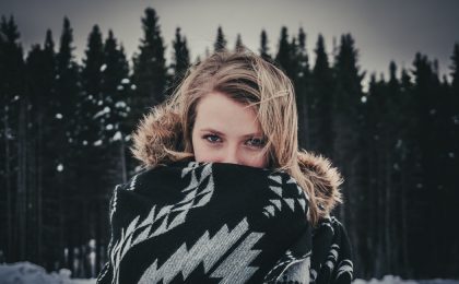 Woman outside in snow wearing blanket.