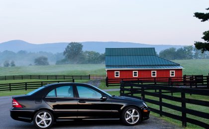 Black sedan with commercial auto insurance in front of a red barn.