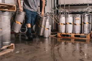 Man dragging kegs over a wet ground and risking a General Liability claim.