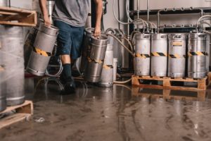 Man dragging kegs over a wet ground and risking a General Liability claim.