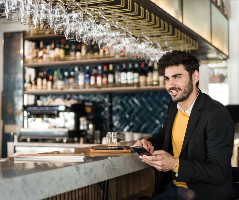 Man in jacket sits at a hotel bar.